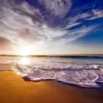 Sunrise over the ocean with waves washing onto a sandy beach, symbolizing peace, reflection, and the enduring legacy of grandparenting