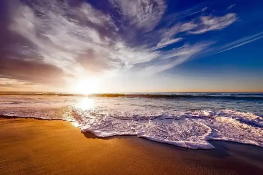 Sunrise over the ocean with waves washing onto a sandy beach, symbolizing peace, reflection, and the enduring legacy of grandparenting