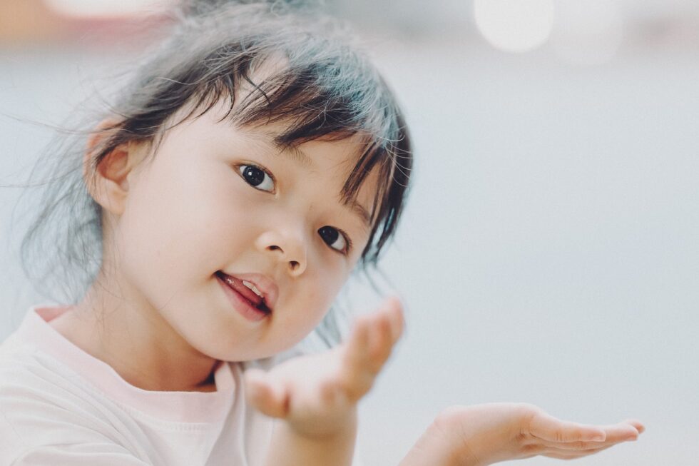 Smiling young granddaughter reaching out toward the camera, showing affection, family connection, and grandparent-grandchild bonding