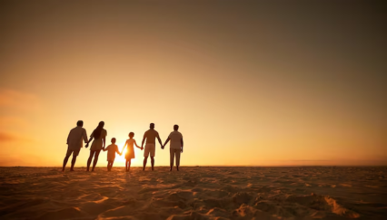 Silhouetted multigenerational family holding hands on a beach at sunset, representing grandparenting, family bonding, and intergenerational connection