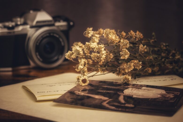 Vintage camera, dried flowers, and old family photographs on a desk, illustrating cherished memories, family history, and grandparenting legacy.