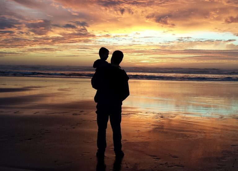 Grandparent carrying a grandchild along the beach at sunset, capturing a peaceful moment of intergenerational love and family bonding.