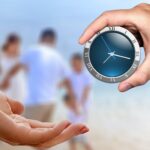 Hands holding a clock in front of a blurred family, symbolizing the importance of making time for family connection and caregiving.