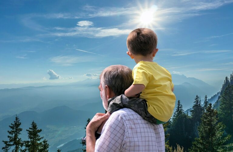 Grandfather carrying his grandson on his shoulders while enjoying a scenic mountain overlook, celebrating intergenerational bonding and outdoor family time.