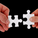 Hands connecting two puzzle pieces to symbolize family support and finding