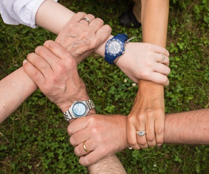 People joining hands in a circle to symbolize family support, connection, and compassionate care