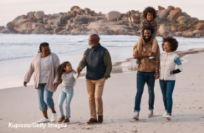 Multigenerational family walking together along a sunny beach, enjoying quality time by the ocean.