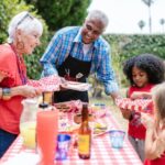 Grandparents enjoying an outdoor picnic with their grandchildren on a sunny day.