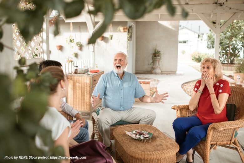 Grandparents sharing a joyful family moment together on a sunny patio.