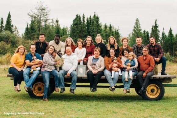 Multigenerational family sitting together on a wagon outdoors, showing grandparents, parents, and children celebrating family bonding and grandparenting connections.