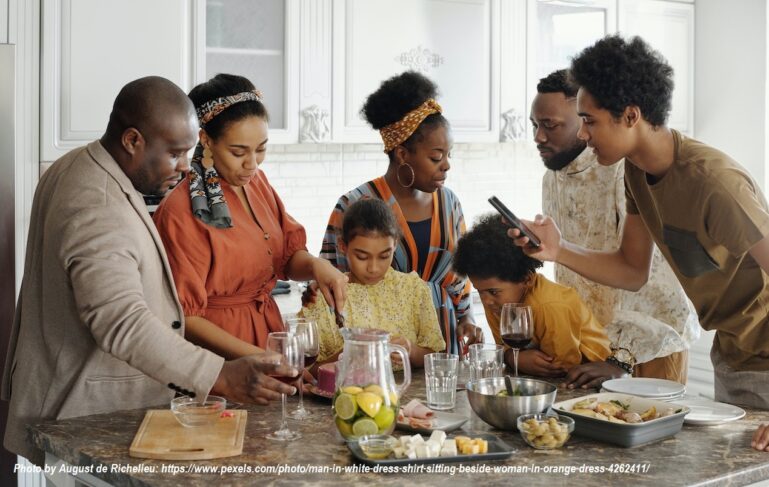 Multigenerational family preparing a meal together in the kitchen, showing grandparents, parents, and children sharing time, learning, and family bonding.