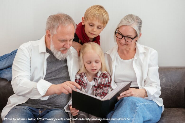 Grandparents reading a family photo album with grandchildren, showing multigenerational bonding, shared memories, and loving grandparenting.