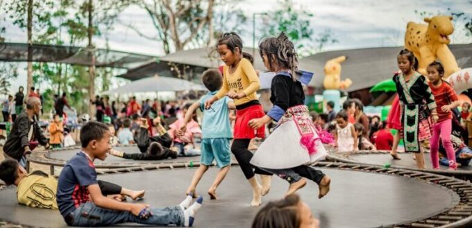 Children playing on a trampoline at a family outdoor event, capturing active grandparenting fun and multigenerational play.