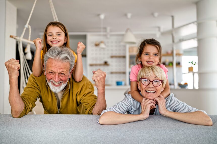 Happy grandparents with two young grandchildren playing together at home, capturing a joyful multigenerational family grandparenting moment.