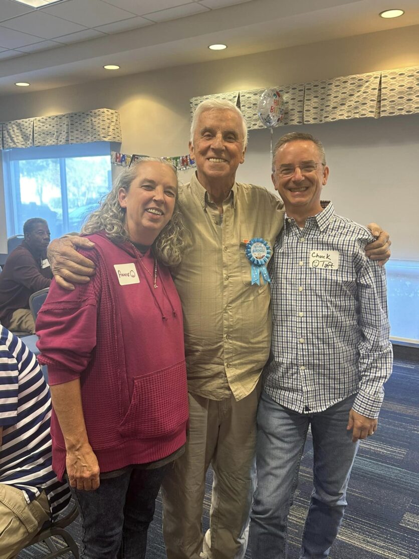 Neil Taft with children Chuck and Annie, posing together at a birthday gathering, showing family celebration, intergenerational connection, and grandparenting.