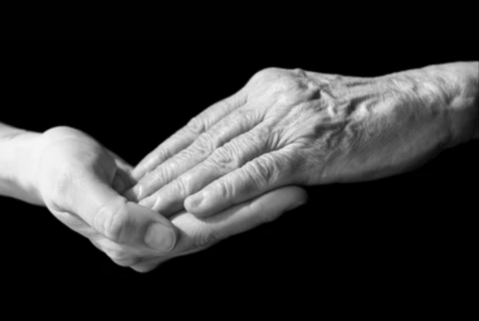 Older adult hand resting in a younger person’s hand, symbolizing grandparenting, support, care, and intergenerational family connection