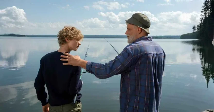 A grandparent and grandchild fishing together, the grandparent listening intently to his grandson.